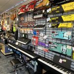 An interior shot of BANG! Music, showing keyboards, digital pianos, guitars, stands, and accessories.